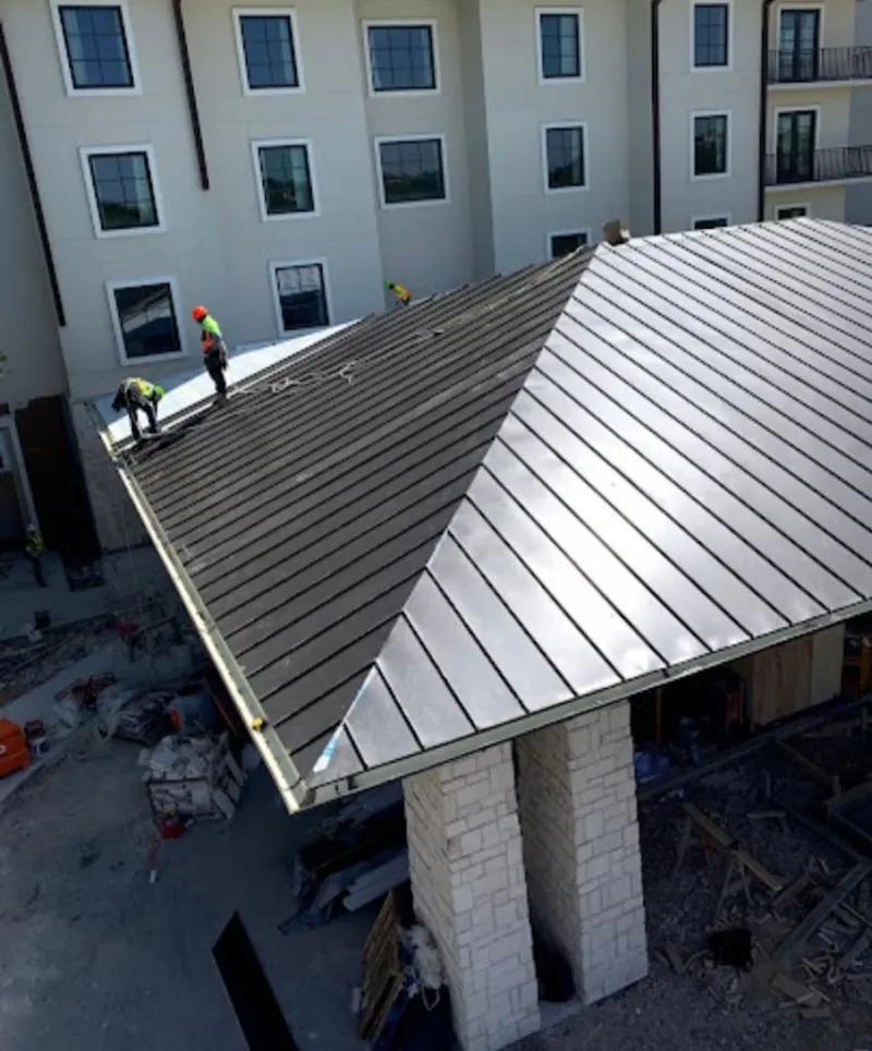 Crew installing standing seam metal roof panels on a commercial project in Weston